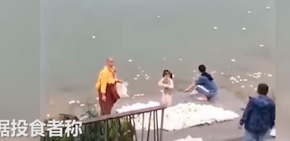 市民不停将大量馒头扔进江中场面惊人 旁边还站着一个僧人